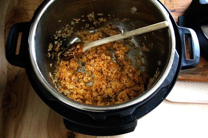 An Instant Pot with rice, harissa, onion, and garlic.