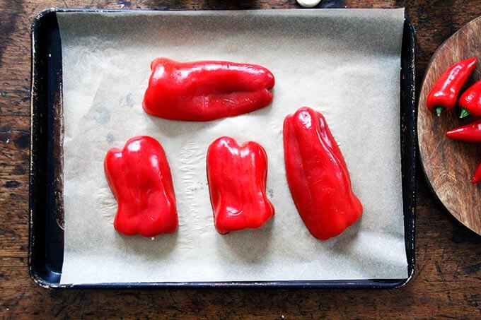 A parchment-lined sheet pan with halved bell peppers.