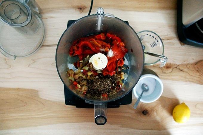 An overhead shot of a food processor holding all of the ingredients to make harissa.