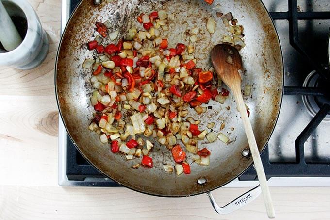 A skillet filled with sautéed onions and chilies caramelizing. 