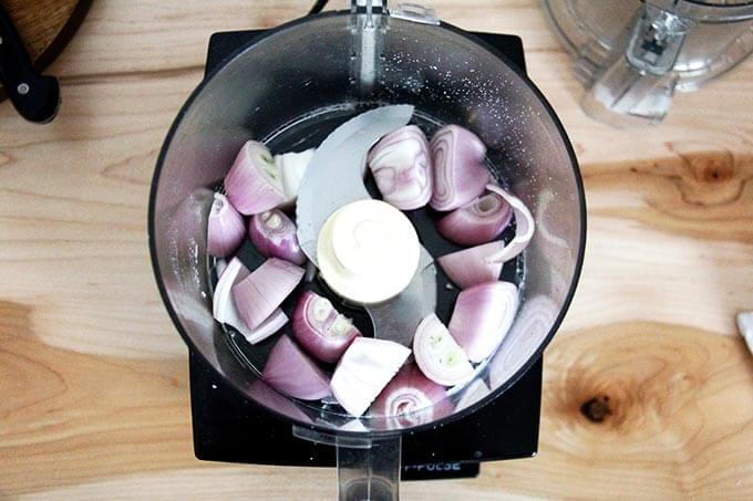 A food processor holding shallots. 