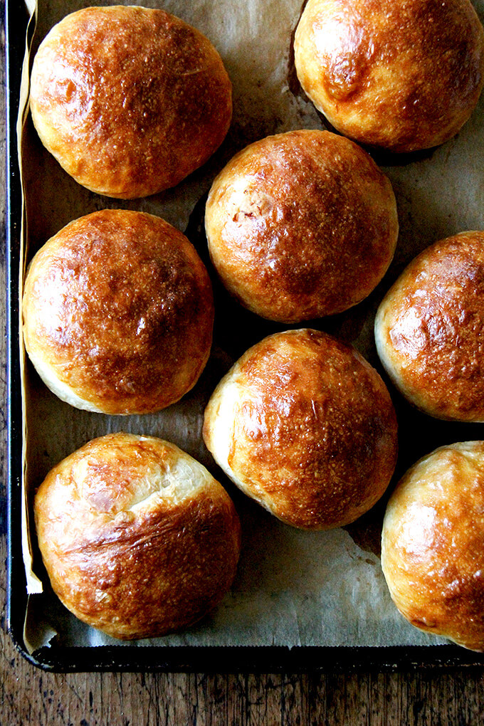 Light brioche buns on a sheet pan.