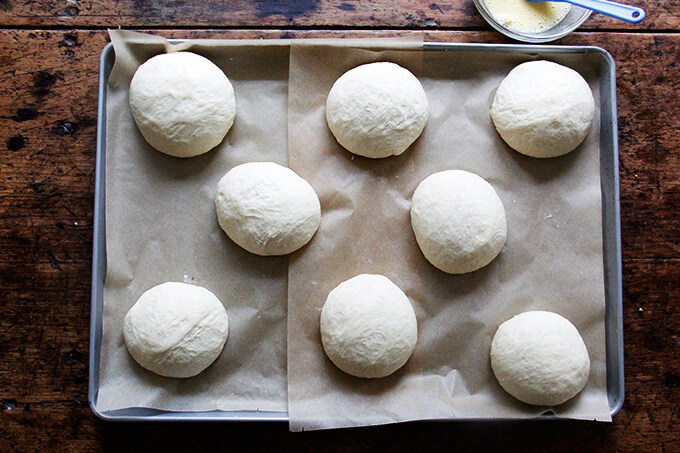 A large sheet pan lined with parchment paper topped with brioche balls.