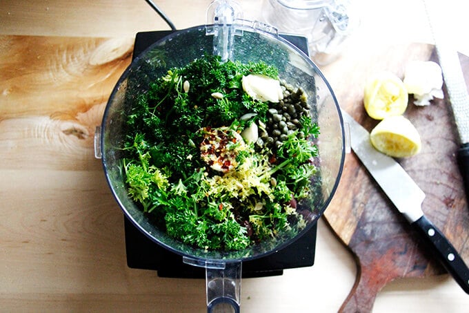 An overhead shot of a food processor holding the ingredients to make black olive tapenade.