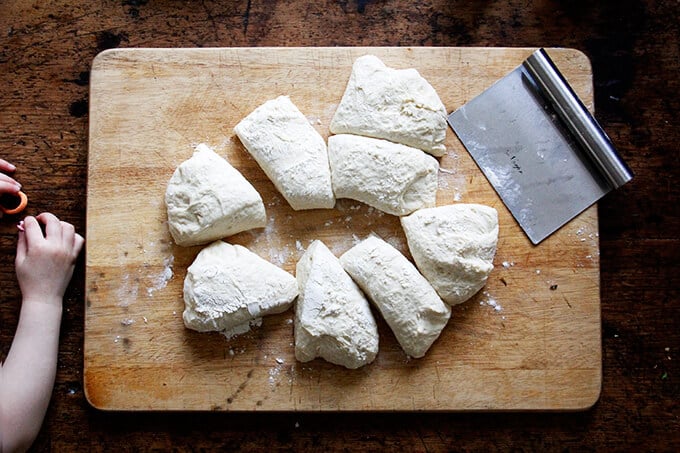 Brioche dough on a board portioned into 8 pieces. 