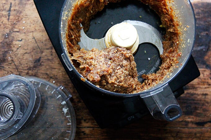 A food processor with a purée of lemon-coconut date ball batter.