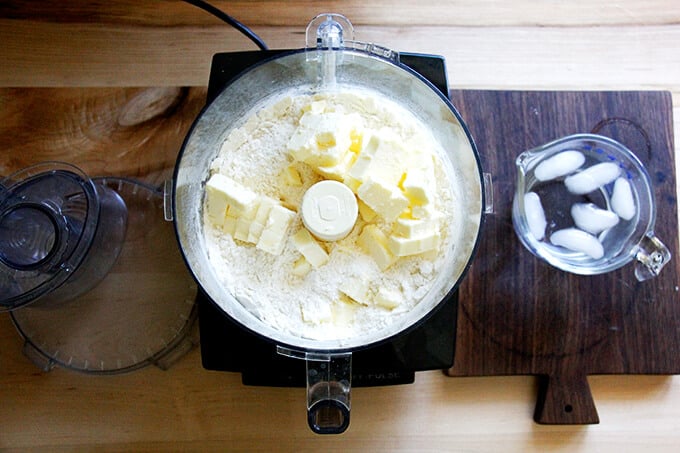 A counter with a food processor filled with the ingredients to make foolproof food processor pastry dough: flour, salt, sugar, and butter.
