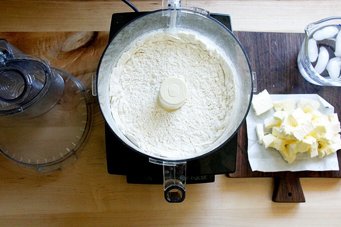A counter with a food processor filled with the ingredients to make foolproof food processor pastry dough.