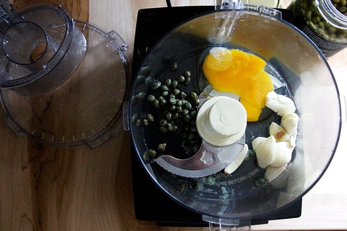 A food processor with ingredients to make classic aioli.