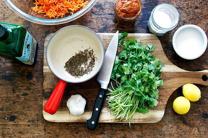 A board with garlic, cilantro, lemon, and cumin.