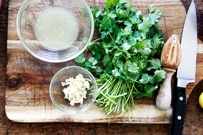 A board with minced garlic, lemon, and cilantro.