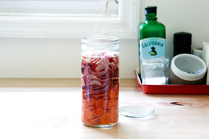 A jar filled with onions, carrots, and pickling liquid. 