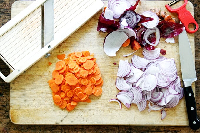 Sliced carrot and onion aside a mandoline. 