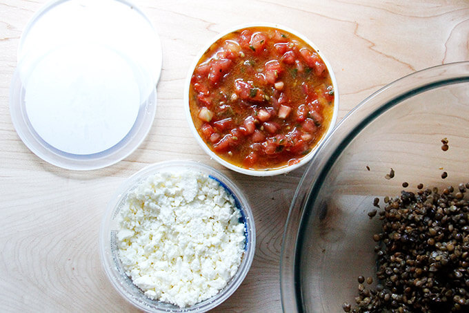 Open tub of bruschetta sauce, open tub of feta, bowl of lentils. 