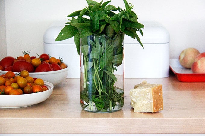 A counter with tomatoes, basil, and parmesan.