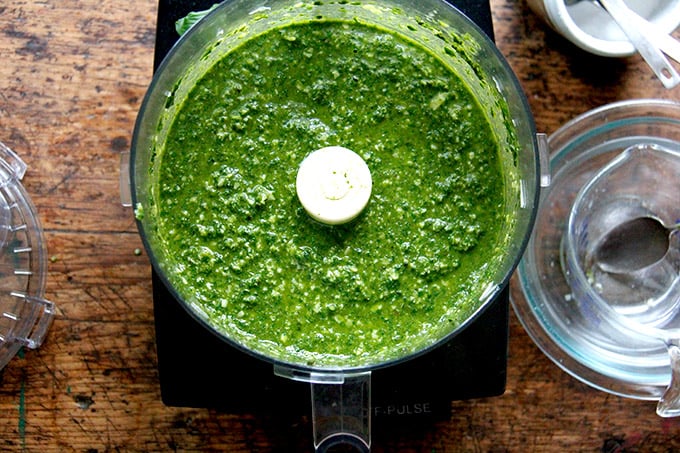 A food processor filled with basil pesto.