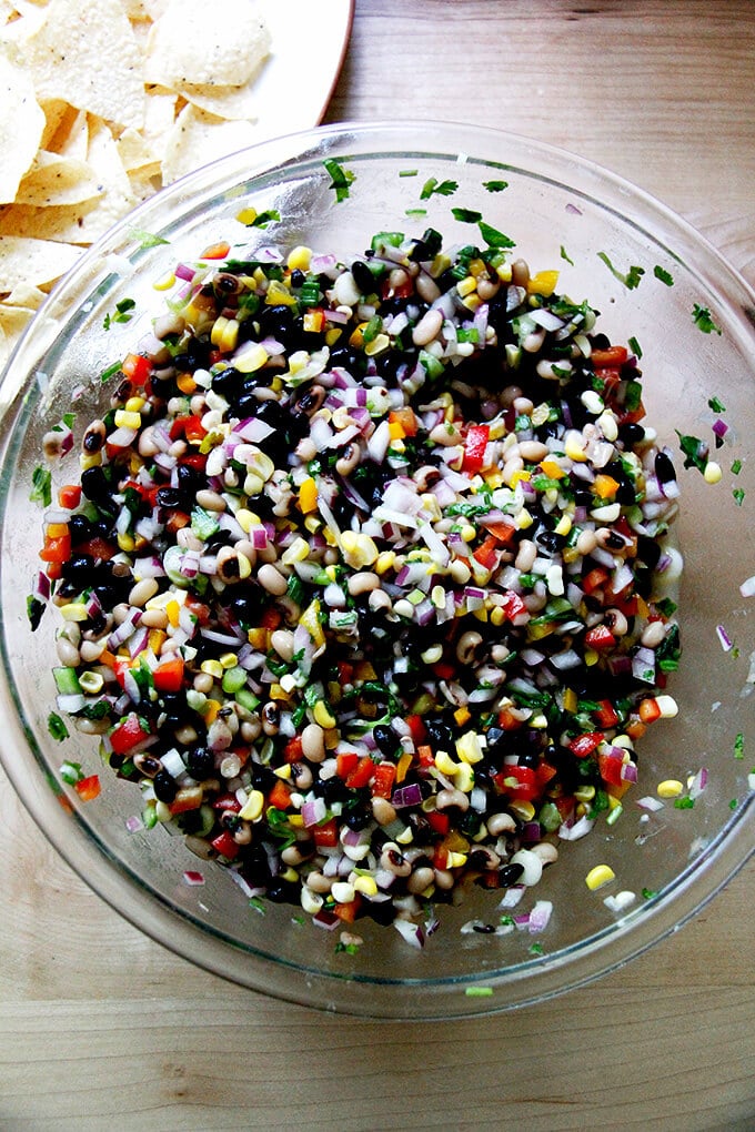 A large bowl filled with Texas caviar aside tortilla chips. 