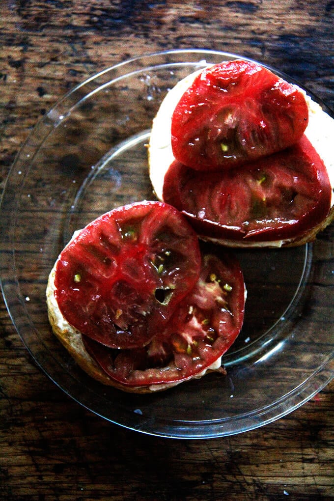 Bagels + cream cheese + tomatoes + salt on a plate. 