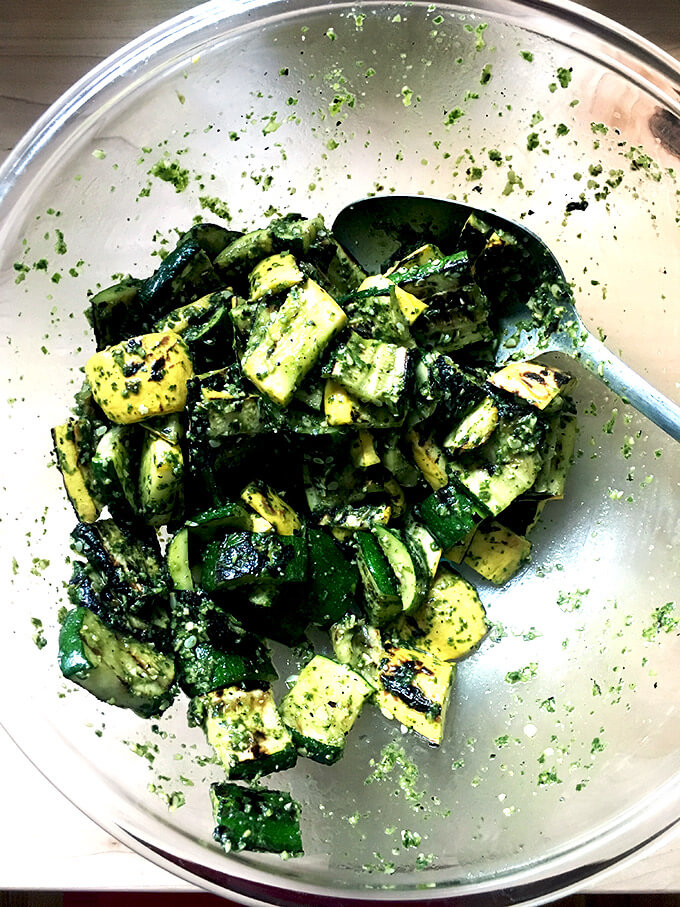 A bowl filled with grilled vegetables tossed with basil pesto. 