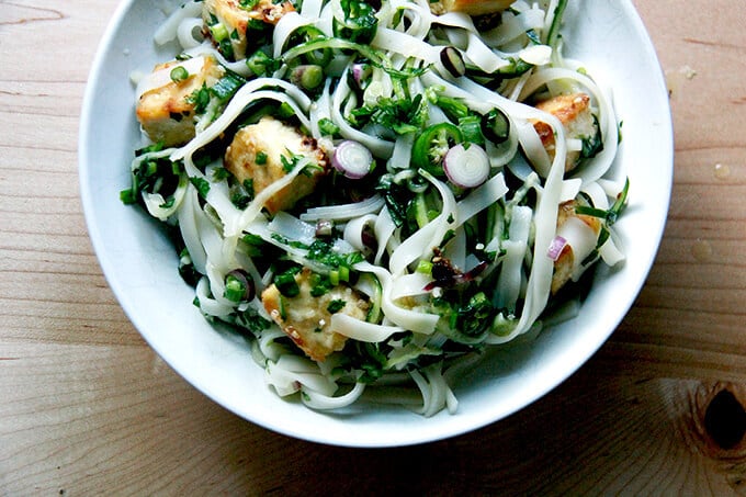 A bowl of rice noodles tossed with nuoc cham, cucumbers, herbs, and crispy tofu. 