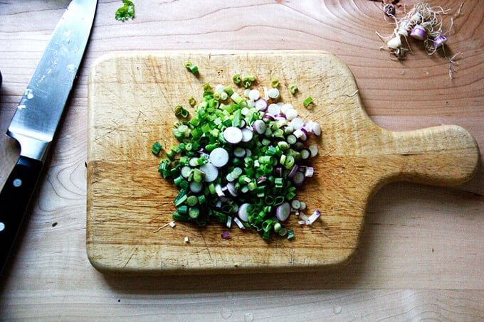 A board filled with sliced scallions. 