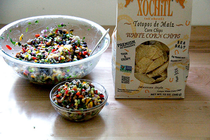 A bowl of Texas caviar aside a bag of Xochitl chips. 