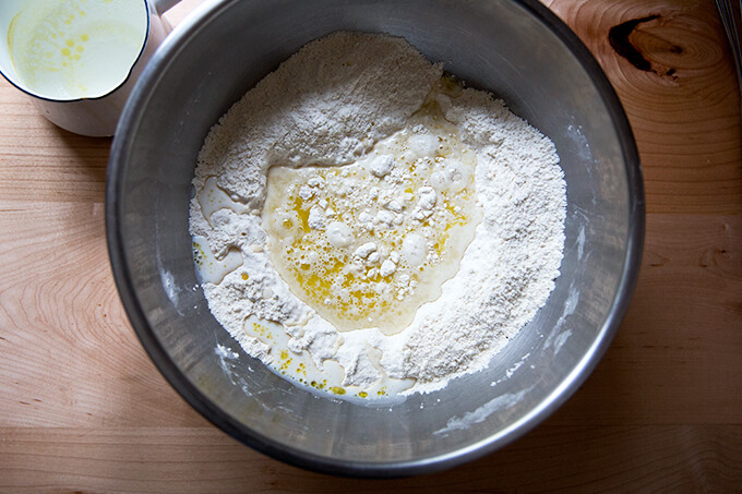 A bowl with flour, salt, yeast, milk, and oil.