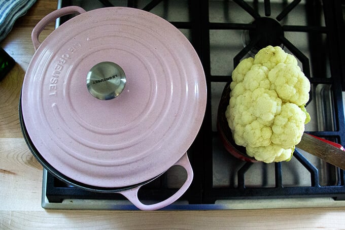 An overhead shot of a Le Creuset Dutch oven aside a head of poached cauliflower.