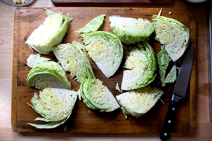 A board with a head of Savoy cabbage cut into wedges.