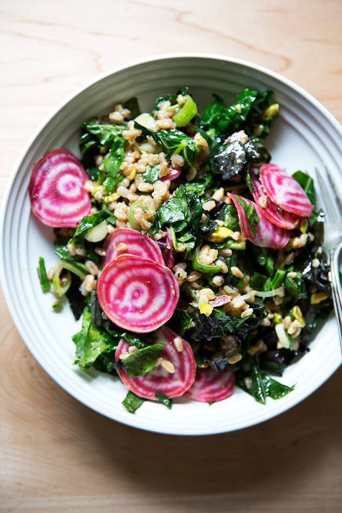 A white bowl filled with Charlie Bird farro salad and sliced raw beets.