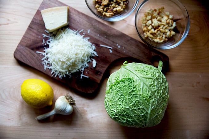 Roasted cabbage wedges ingredients on the counter: grated parmesan, cabbage, lemon, garlic, bread crumbs, walnuts. 