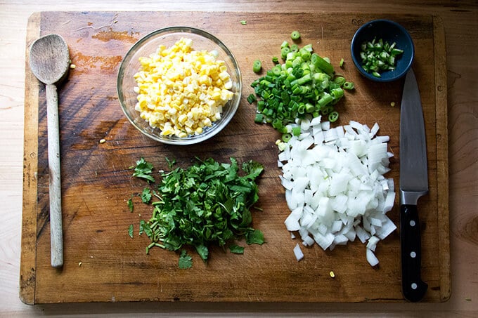 Prepped ingredients: chopped onions, scallions, herbs, chili and corn.