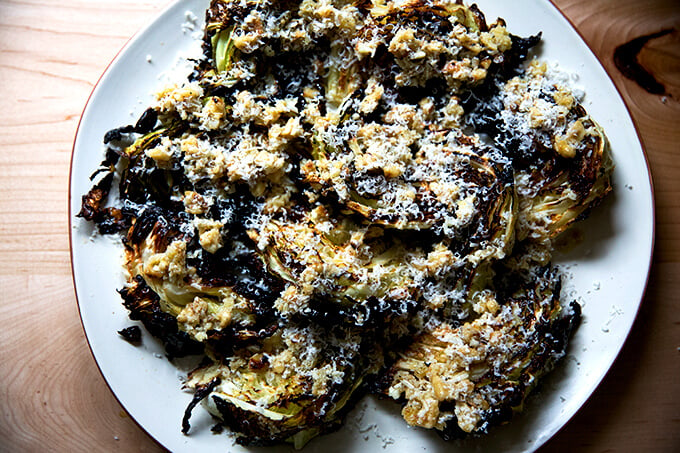 A platter of roasted cabbage wedges topped with walnut salsa and parmesan.