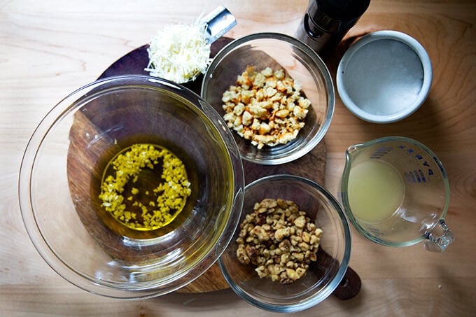 The ingredients for a walnut salsa: olive oil, minced garlic, parmesan, bread crumbs, walnuts, lemon, salt, and pepper. 