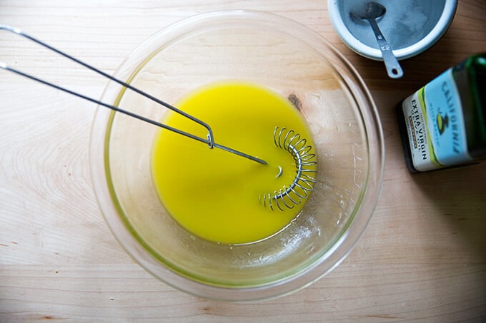 A bowl of lemon dressing stirred together with a whisk.