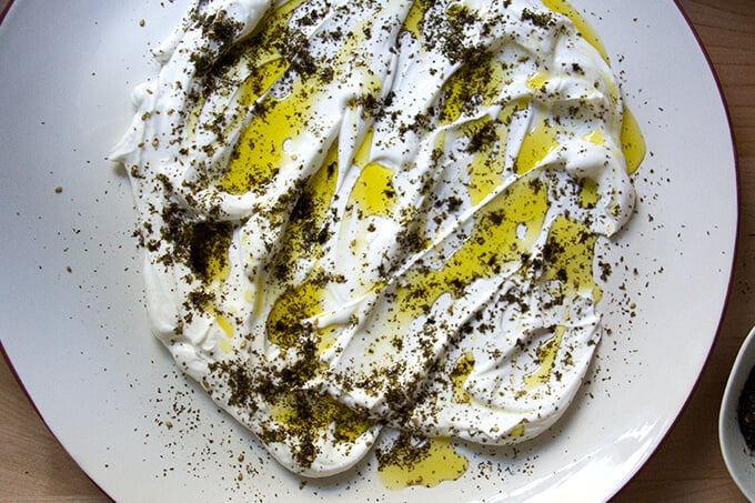 A platter smeared with lemony yogurt sauce, olive oil, and za'atar.