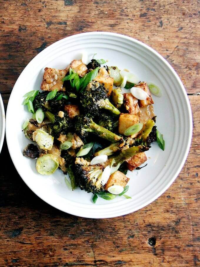 A bowl of crispy tofu and broccoli with peanut sauce.