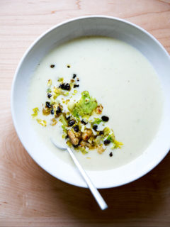 An overhead shot of a bowl of cream of celery soup with walnut salsa.