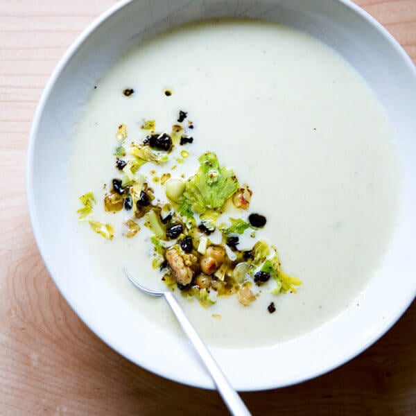 An overhead shot of a bowl of cream of celery soup with walnut salsa.