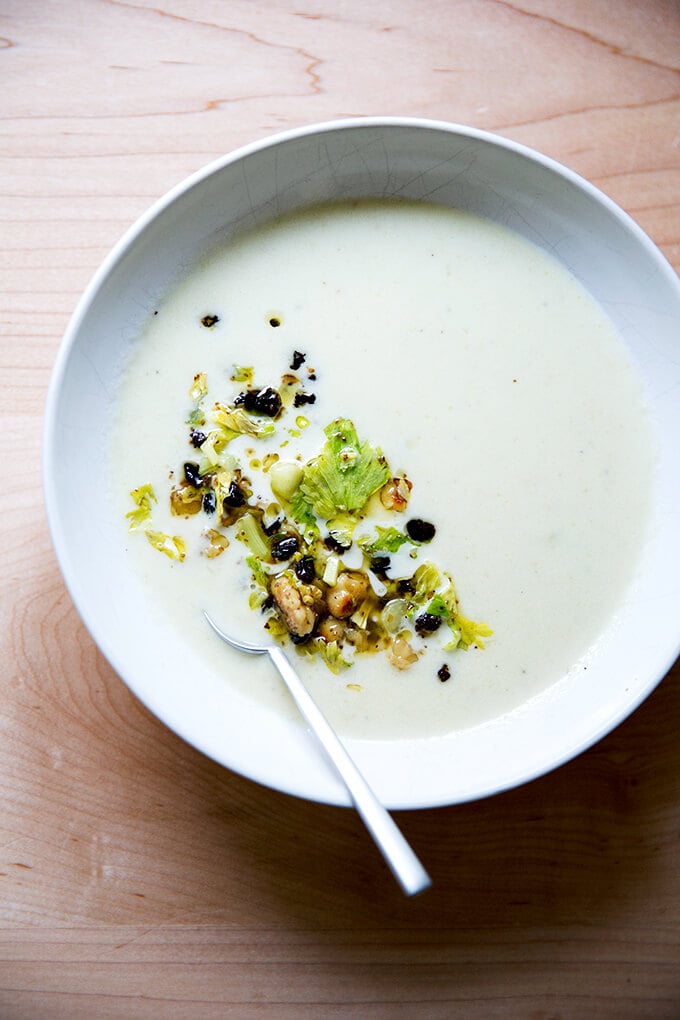 An overhead shot of a bowl of cream of celery soup with walnut salsa.