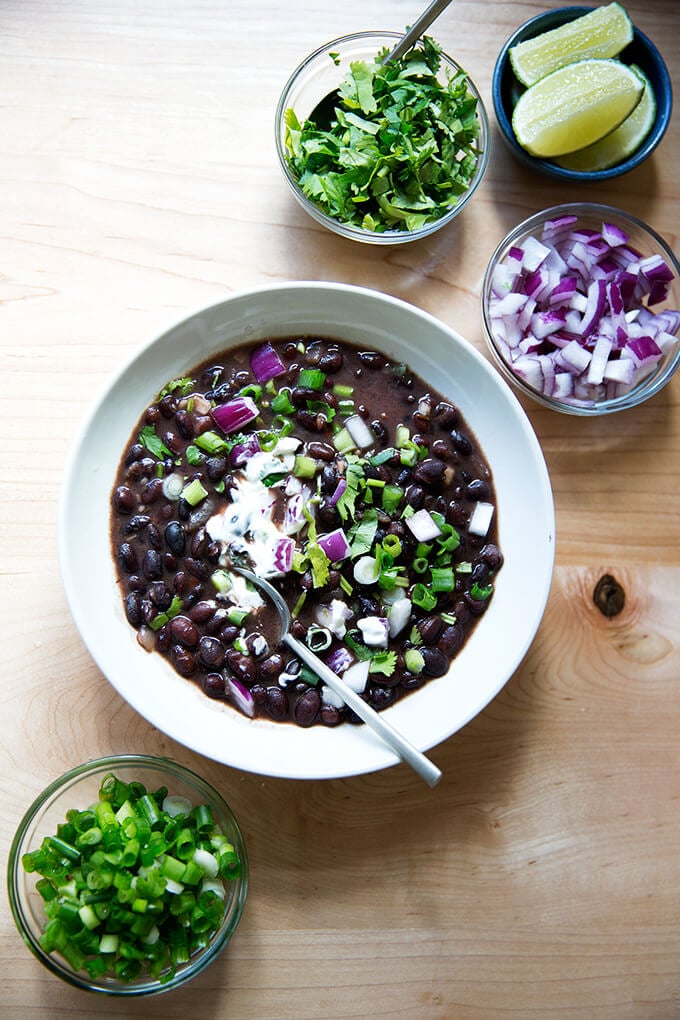 A bowl of black bean soup with garnishes. 