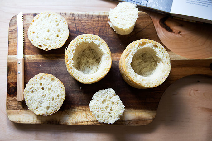 An overhead shot of two hollowed out loaves of breads and their caps, ready to be turned into bread bowls.