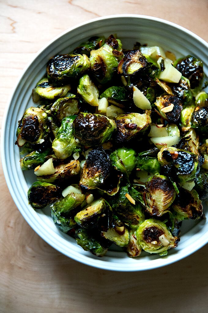 A serving bowl of roasted Brussels sprouts, almonds, and Manchego all tossed together.