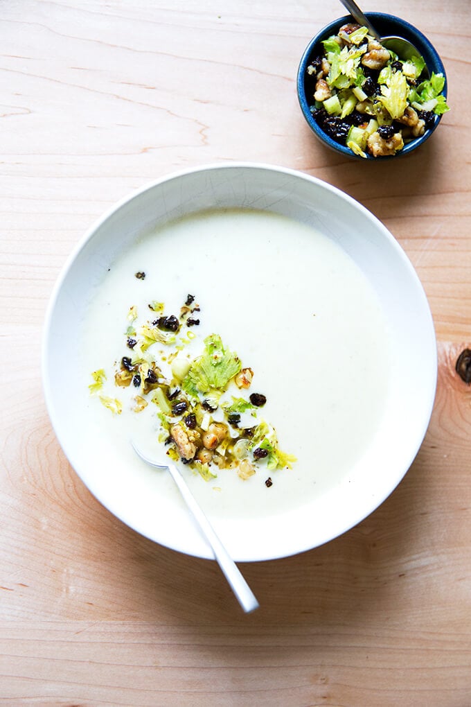 An overhead shot of a bowl of cream of celery soup with walnut salsa.