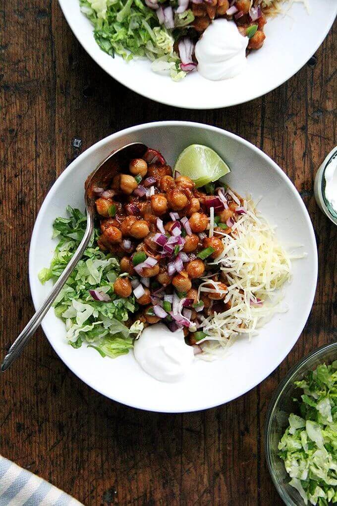 A bowl of chickpea tacos aside lettuce and cheese. 