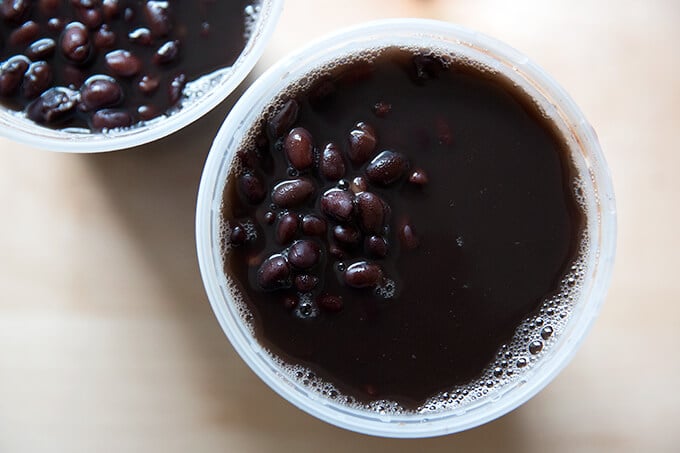 Two quart containers holding pressure-cooked black beans. 