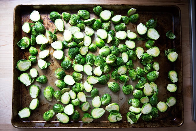 A sheet pan spread with halved Brussels sprouts, olive oil, and salt.