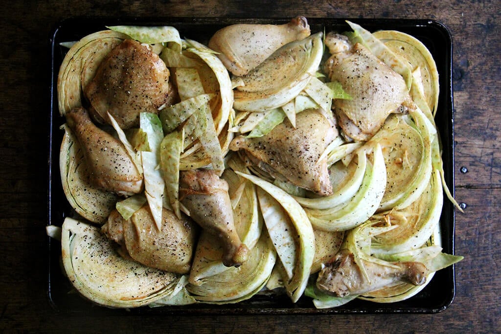 A sheet pan of cabbage and chicken legs.