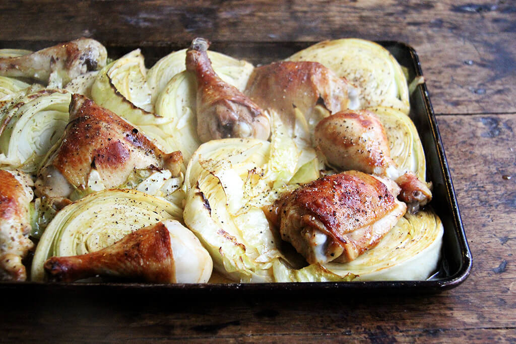 A sheet pan of roasted chicken and cabbage wedges.