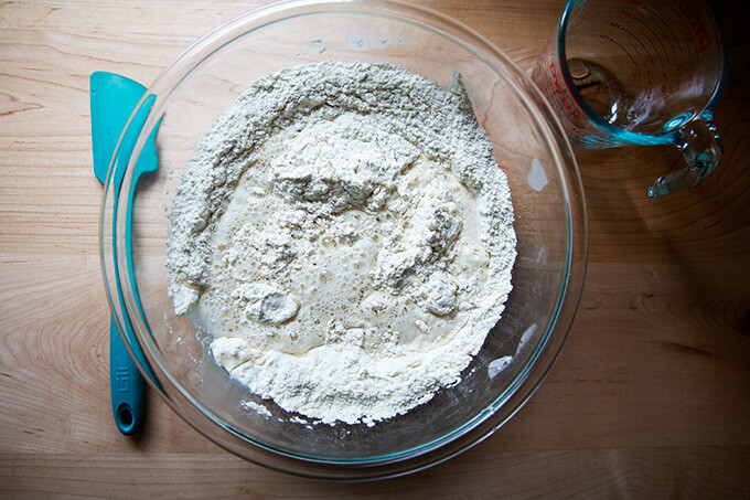 A bowl filled with dry ingredients and water to make a simple, homemade pizza dough recipe. 